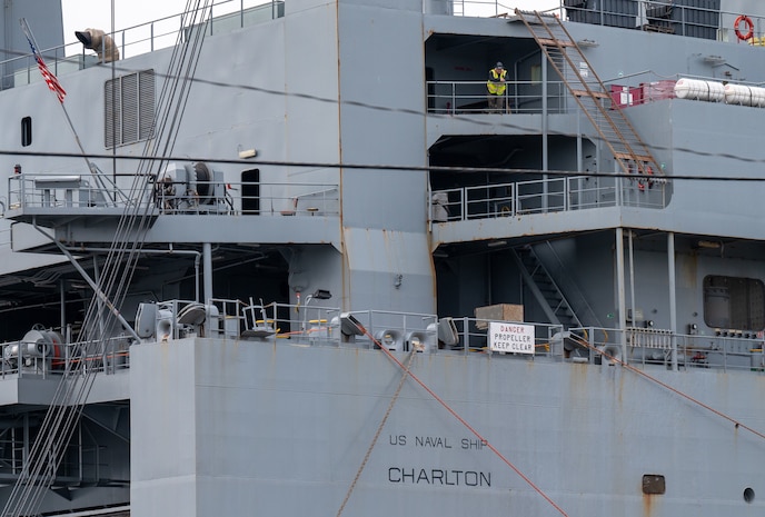 A photo of a man looking out from a balcony of a ship.