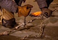 A photo of a man securing a vehicle with chains.