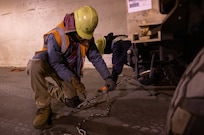 A photo of two men securing a vehicle with chains.