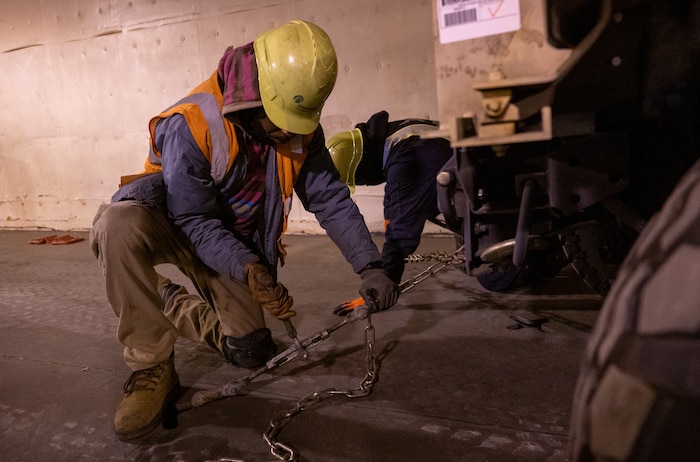 A photo of two men securing a vehicle with chains.