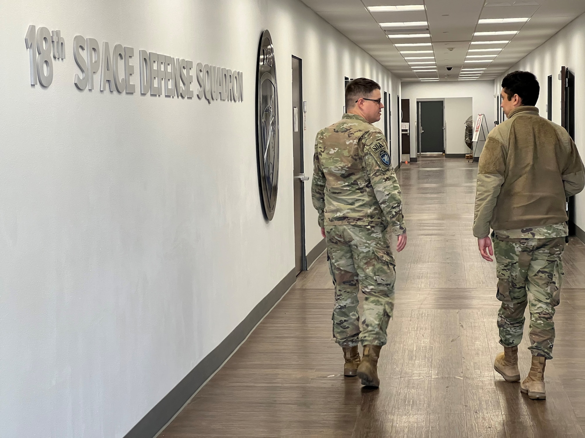 U.S. Space Force Tech. Sgt. Nathaniel McCready, flight chief for Space Delta 2 – Space Domain Awareness and Space Battle Management’s 18th Space Defense Squadron, left, passes the squadron’s emblem while chatting with a fellow 18 SDS Guardian at Vandenberg Space Force Base, California, March 22, 2024. After transferring from the Army to the Space Force in 2022, McCready worked with squadron leadership to develop the Guardian-Airmen Apprenticeship Program, an initiative to provide systematic, targeted development for junior leaders. (U.S. Space Force photo by Julian Labit)