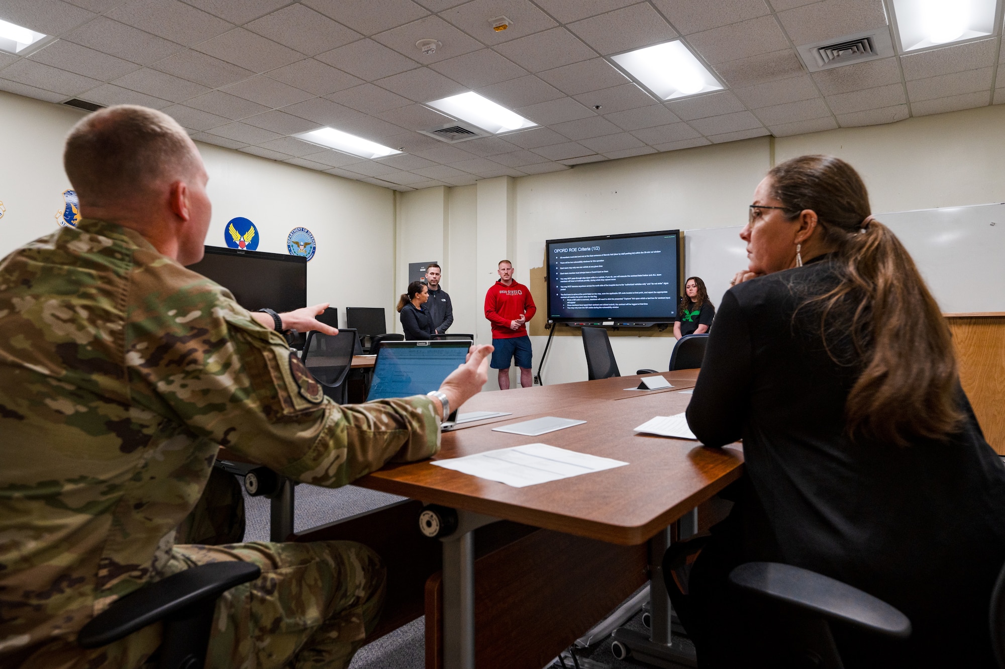 An instructional coach listens as U.S. Air Force Capt. Gregory Hutchins, 333rd Training Squadron instructor, gives students feedback on a strategic and tactical planning brief at Keesler Air Force Base, Mississippi, March 18, 2024.