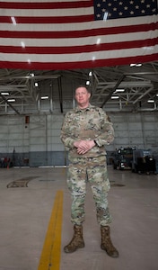 An Airman stands in front of a large American Flag.
