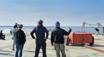 Sailors assigned to the Pre-Commissioning Unit John F. Kennedy (CVN 79) work alongside HII and Naval Air Systems Command counterparts during the first “dead-load” testing of the electromagnetic aircraft launch system. In this phase of testing, large, wheeled, car-like structures of graduated weights up to 80,000 pounds to simulate the weight of actual aircraft are launched off the carrier’s bow into the James River.