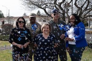 A group of people pose for a photo behind bubbles while holding pinwheels.