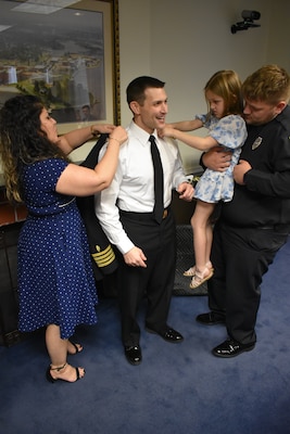Wife Marilisse, daughter Emilia and son Caleb help Capt. Barnes get into his prescribed uniform after being frocked to his current rank.