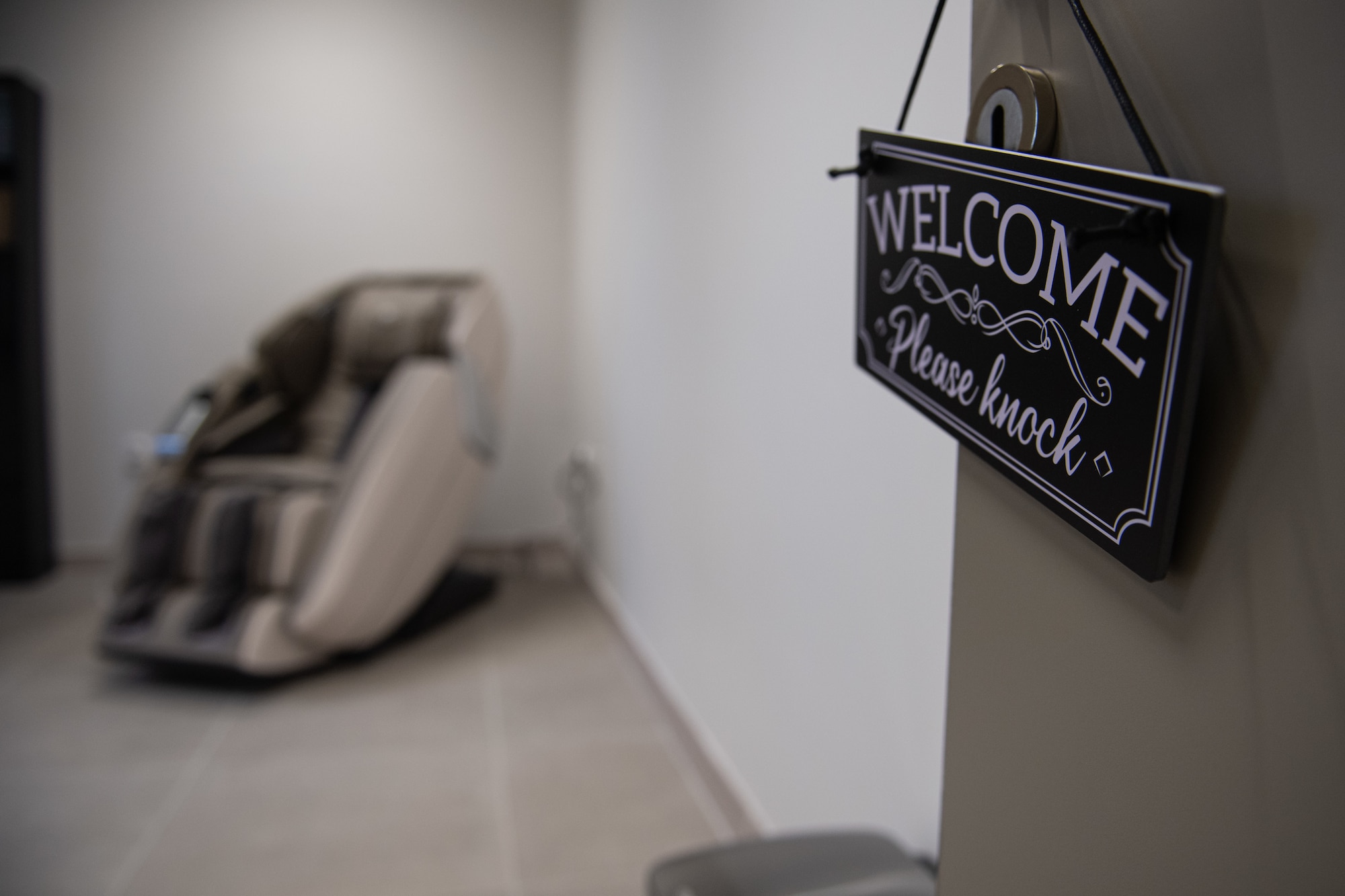 A welcome sign hangs on a door inside the new Operational Support Team building at Incirlik Air Base, Türkiye, March 27, 2024. The door is open and in the background there is a massage chair.