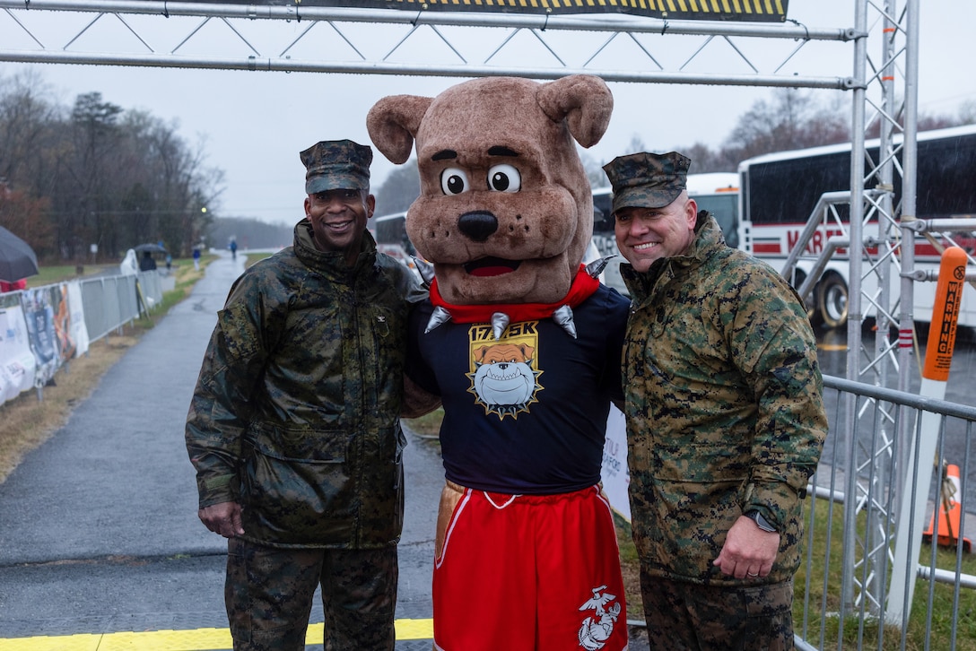 U.S. Marine Corps Col. Michael L. Brooks, a native of South Boston, Virginia, commanding officer of Marine Corps Base Quantico, and Sgt. Maj. Michael R. Brown, a native of Jacksonville, Florida, sergeant major of MCBQ, pose for a group photo with Miles, Marine Corps Marathon mascot, during the MCM 17.75k at Prince William Forest Park, Virginia, March 23, 2024. The distance of the race commemorates the year the Marine Corps was established, 1775, and offers finishers “Access Granted” passes, guaranteeing entry to the 49th MCM. (U.S. Marine Corps photo by Lance Cpl. Ethan Miller)