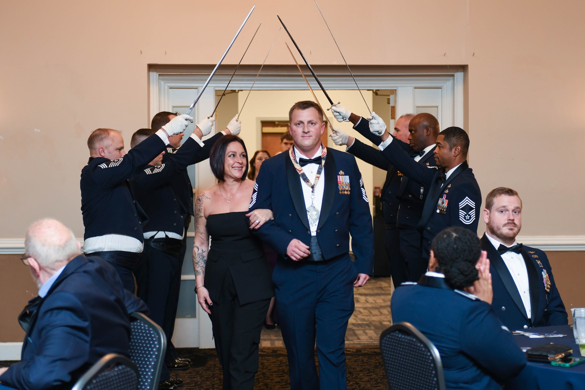 U.S. Air Force Chief Master Sgt. Nicholas Caldwell, select, with the 4th Civil Engineer Squadron, enters with his spouse, Gilma, through a saber cordon during the chief master sergeant recognition ceremony at Seymour Johnson Air Force Base, North Carolina, March 2, 2024. The rank of chief master sergeant was established by Congress in 1958. They are responsible for embodying the Air Force core values and possess attributes needed to serve at the highest enlisted grade. (U.S. Air Force photo by Senior Airman Taylor Hunter)