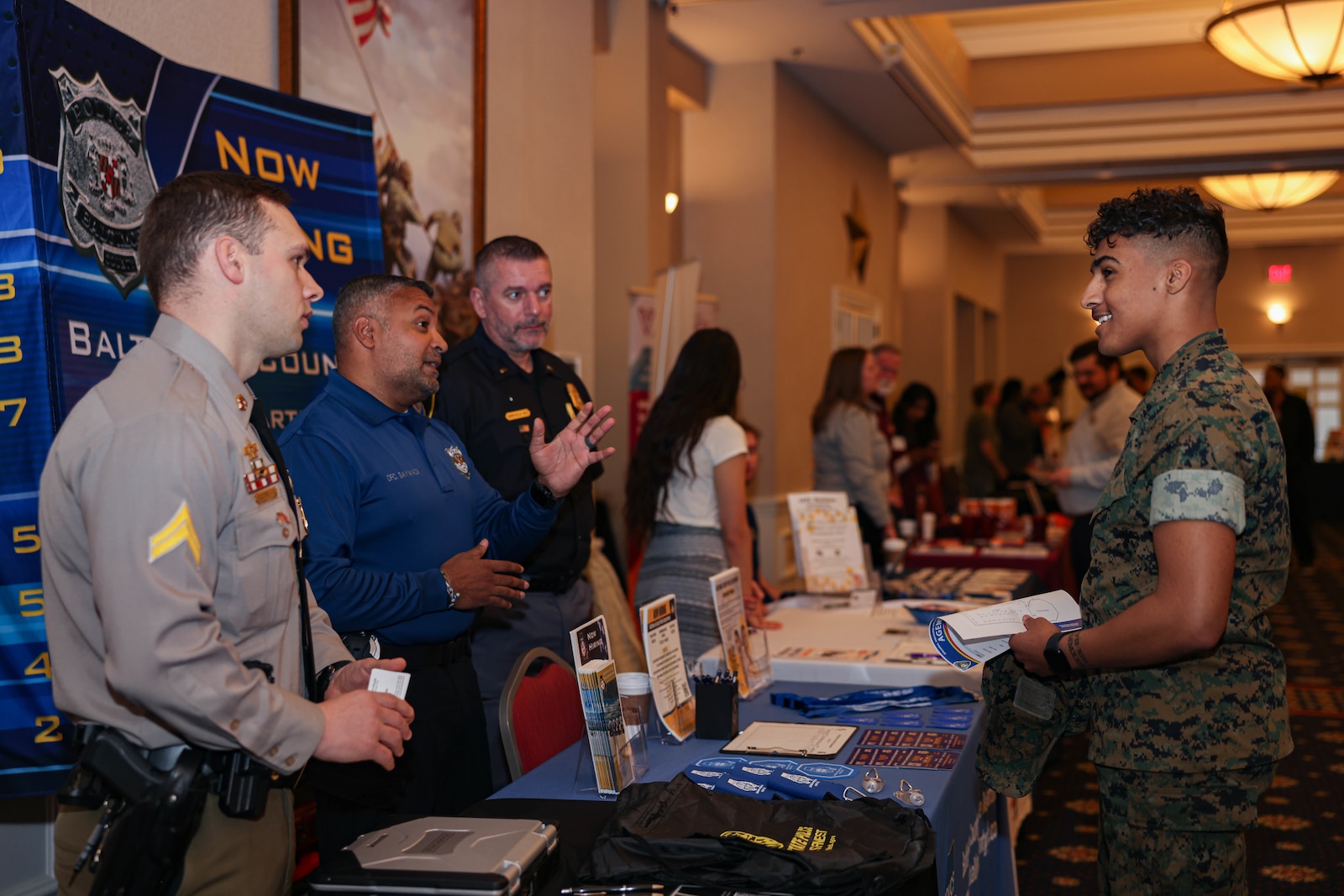 Police Officers with Baltimore County speak to a U.S. Marine with the Wounded Warrior Regiment during the 2024 Wounded Warrior Education, Internship and Career Recourse Fair at the Clubs of Quantico on Marine Corps Base Quantico, Virginia, March 27, 2024. The resource fair provides Wounded Warriors transitioning out of the military, various connections and opportunities to help them in future endeavors. (U.S. Marine Corps photo by Lance Cpl. David Brandes)