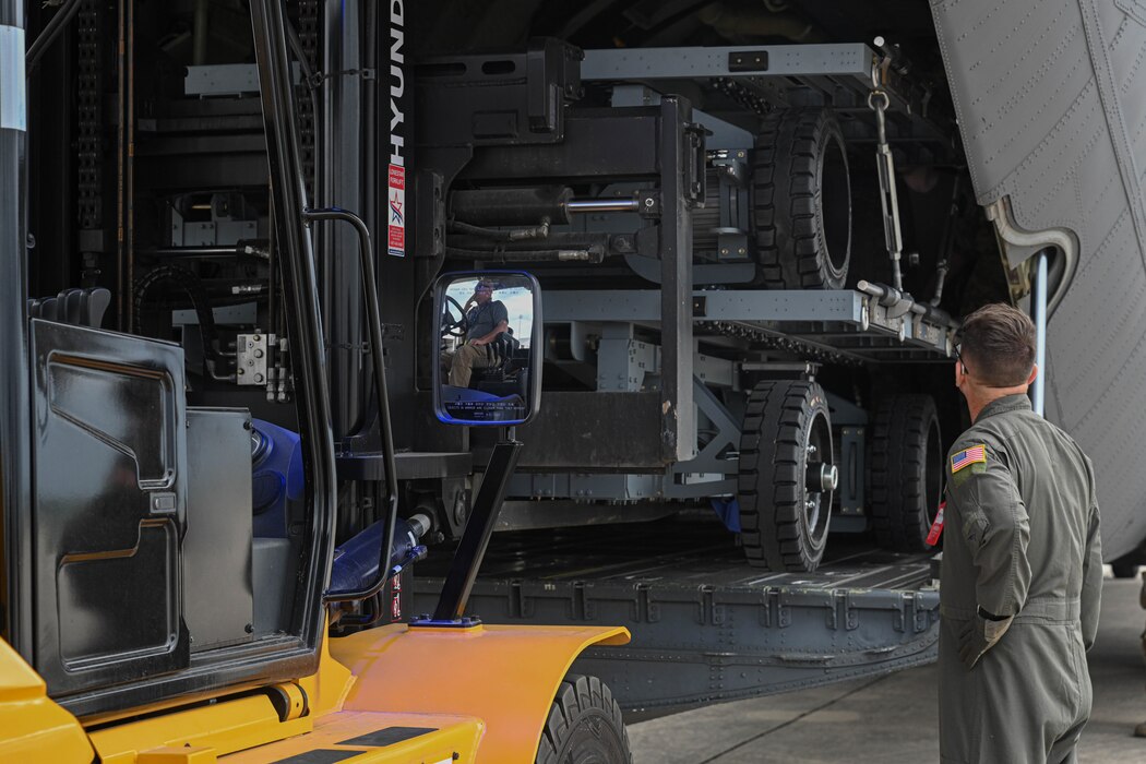 An Airman watches a cargo loader forklifted on an aircraft
