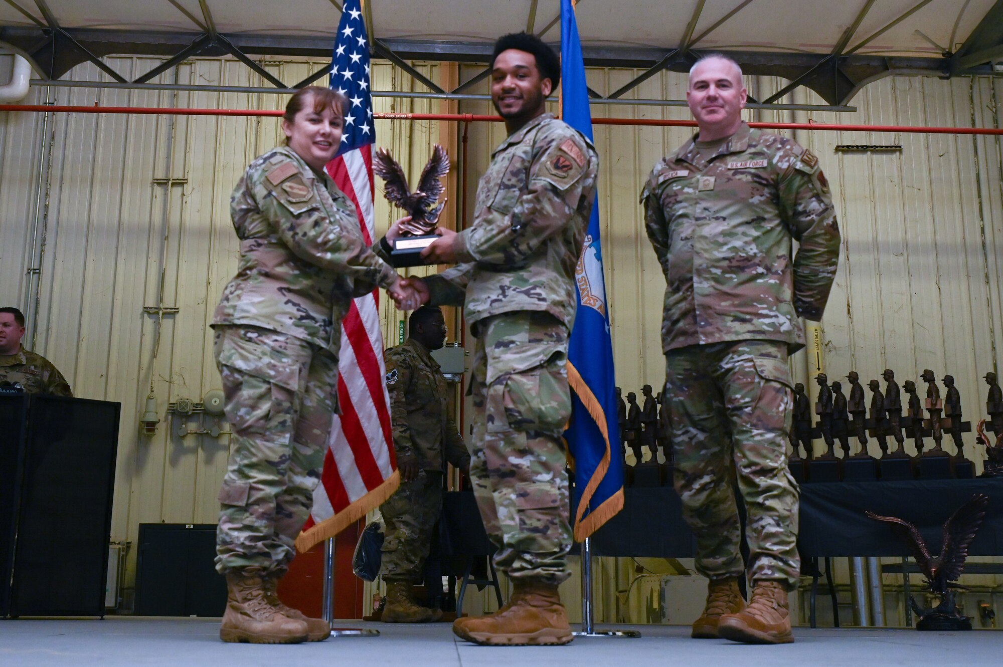 Airman 1st Class Riley Domaingue, center, assigned to the 4th Maintenance Operations Flight, receives the Analyst of the Year award from Col. Kathryn Roman, 4th Maintenance Group commander and Chief Master Sgt. Michael Bylica, 4 MXG senior enlisted leader, during the 4 MXG Maintenance Person of the Year ceremony at Seymour Johnson Air Force Base, North Carolina, Mar. 08, 2024. The MPOY ceremony recognized Airmen from multiple maintenance career fields and highlighted their accomplishments. (U.S. Air Force photo by Airman Rebecca Tierney)