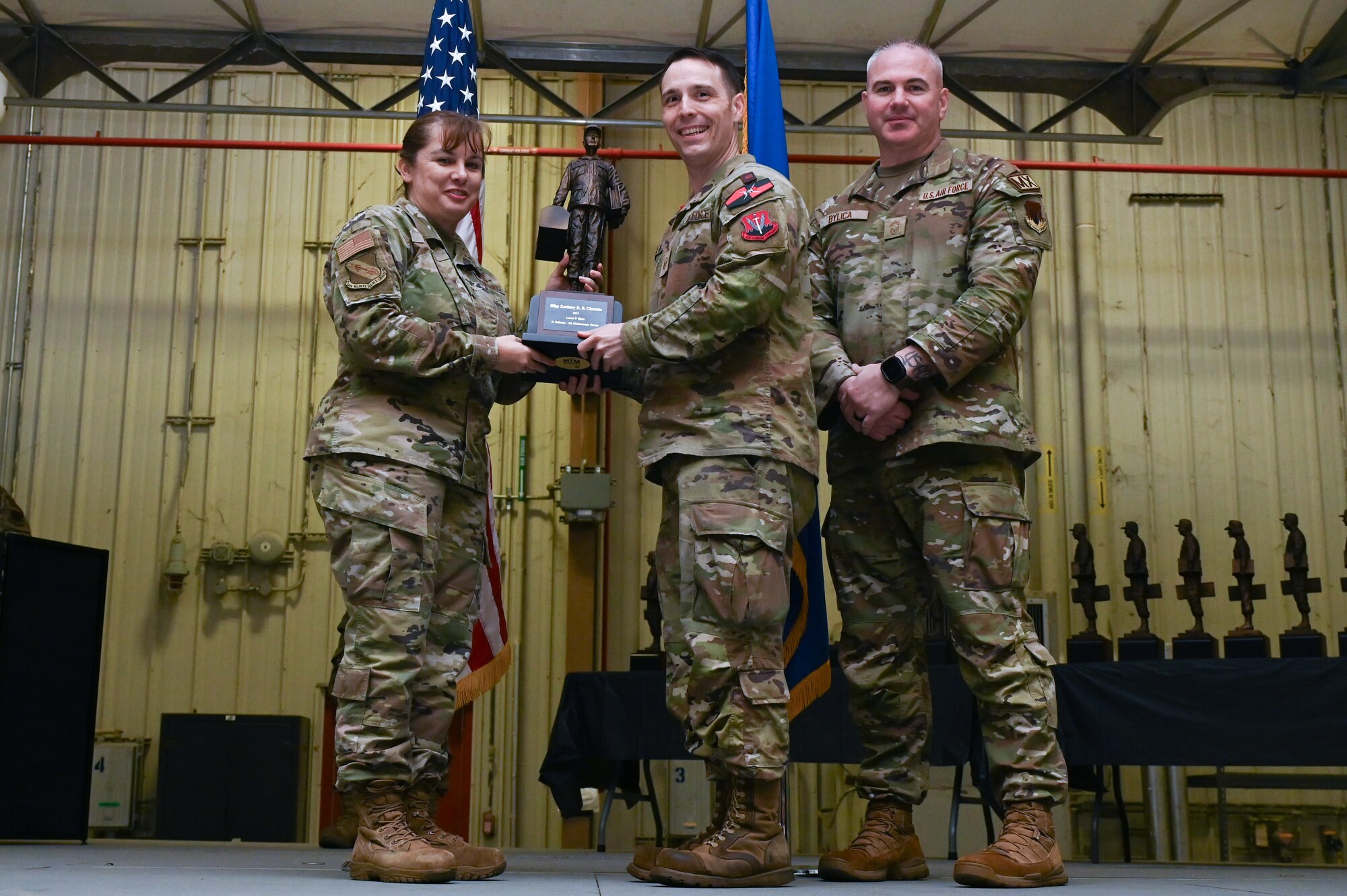 Staff Sgt. Zachary Charette, center, assigned to the 333rd Fighter Generation Squadron, receives the Lance P. Sijan award from Col. Kathryn Roman, 4th Maintenance Group commander and Chief Master Sgt. Michael Bylica, 4 MXG senior enlisted leader, during the 4 MXG Maintenance Person of the Year ceremony at Seymour Johnson Air Force Base, North Carolina, Mar. 08, 2024. The 4th Maintenance Group hosts the event annually for MXG Airmen to celebrate their achievements and hard work. (U.S. Air Force photo by Airman Rebecca Tierney)