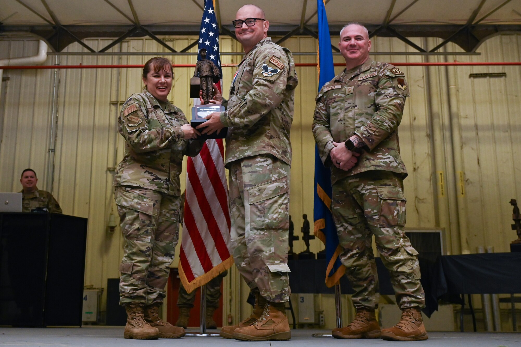 Capt. Nicholas Loftin, center, assigned to the 336th Fighter Generation Squadron, receives the Lt. General Leo Marquez award from Col. Kathryn Roman, 4th Maintenance Group commander and Chief Master Sgt. Michael Bylica, 4 MXG senior enlisted leader, during the 4 MXG Maintenance Person of the Year ceremony at Seymour Johnson Air Force Base, North Carolina, Mar. 08, 2024. The 4th Maintenance Group hosts the event annually for MXG Airmen to celebrate their achievements and hard work. (U.S. Air Force photo by Airman Rebecca Tierney)