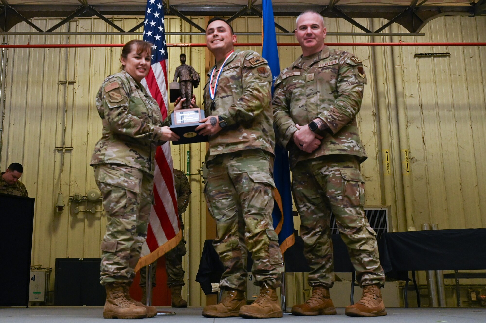 Tech. Sgt. Daniel Vasquez, assigned to the 336th Fighter Generation Squadron, receives the Lt. General Leo Marquez award from Col. Kathryn Roman, 4th Maintenance Group commander and Chief Master Sgt. Michael Bylica, 4 MXG senior enlisted leader, during the 4 MXG Maintenance Person of the Year ceremony at Seymour Johnson Air Force Base, North Carolina, Mar. 08, 2024. The 4th Maintenance Group hosts the event annually for MXG Airmen to celebrate their achievements and hard work. (U.S. Air Force photo by Airman Rebecca Tierney)