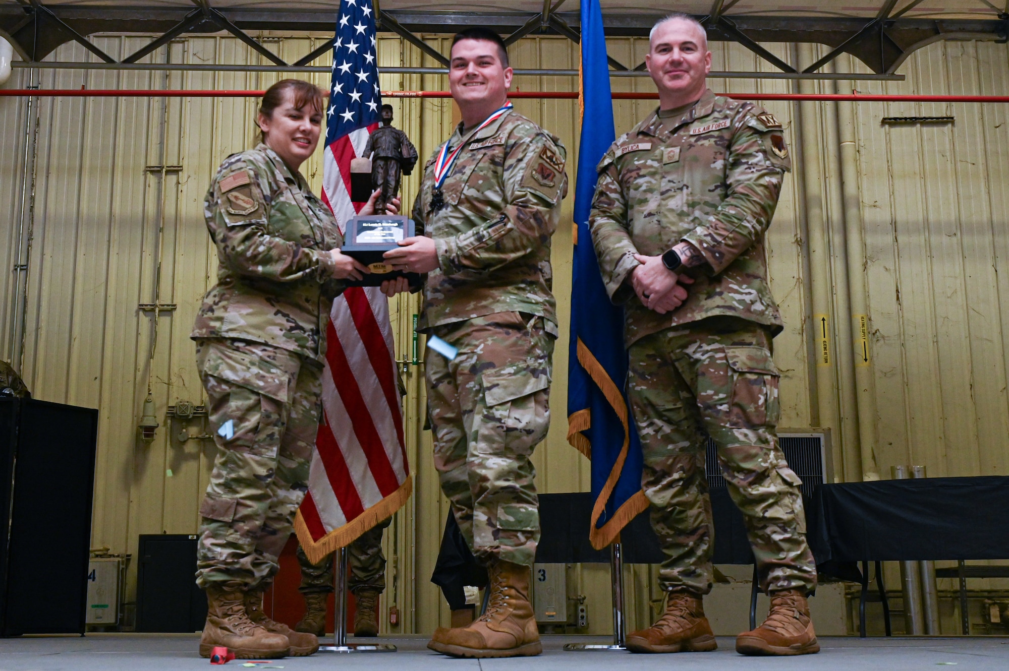 1st Lt. Lonnie Stumbaugh, assigned to the 336th Fighter Generation Squadron, receives the Maintenance Professional of the Year award from Col. Kathryn Roman, 4th Maintenance Group commander and Chief Master Sgt. Michael Bylica, 4 MXG senior enlisted leader, during the 4 MXG Maintenance Person of the Year ceremony at Seymour Johnson Air Force Base, North Carolina, Mar. 08, 2024. The 4th Maintenance Group hosts the event annually for MXG Airmen to celebrate their achievements and hard work. (U.S. Air Force photo by Airman Rebecca Tierney)