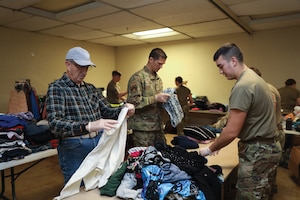(left to right) Arnold Sisca, civilian volunteer, Tech. Sgt. Lucas Pickens, 445th Maintenance Squadron aircraft fuel systems craftsman, and Tech. Sgt. Nicholas Whiting, 445th MXS hydraulic specialist, sort and fold donated clothing items at the Bridges of Hope homeless shelter in Xenia, Ohio, March 10, 2024. (U.S. Air Force photo/Senior Airman Angela Jackson)