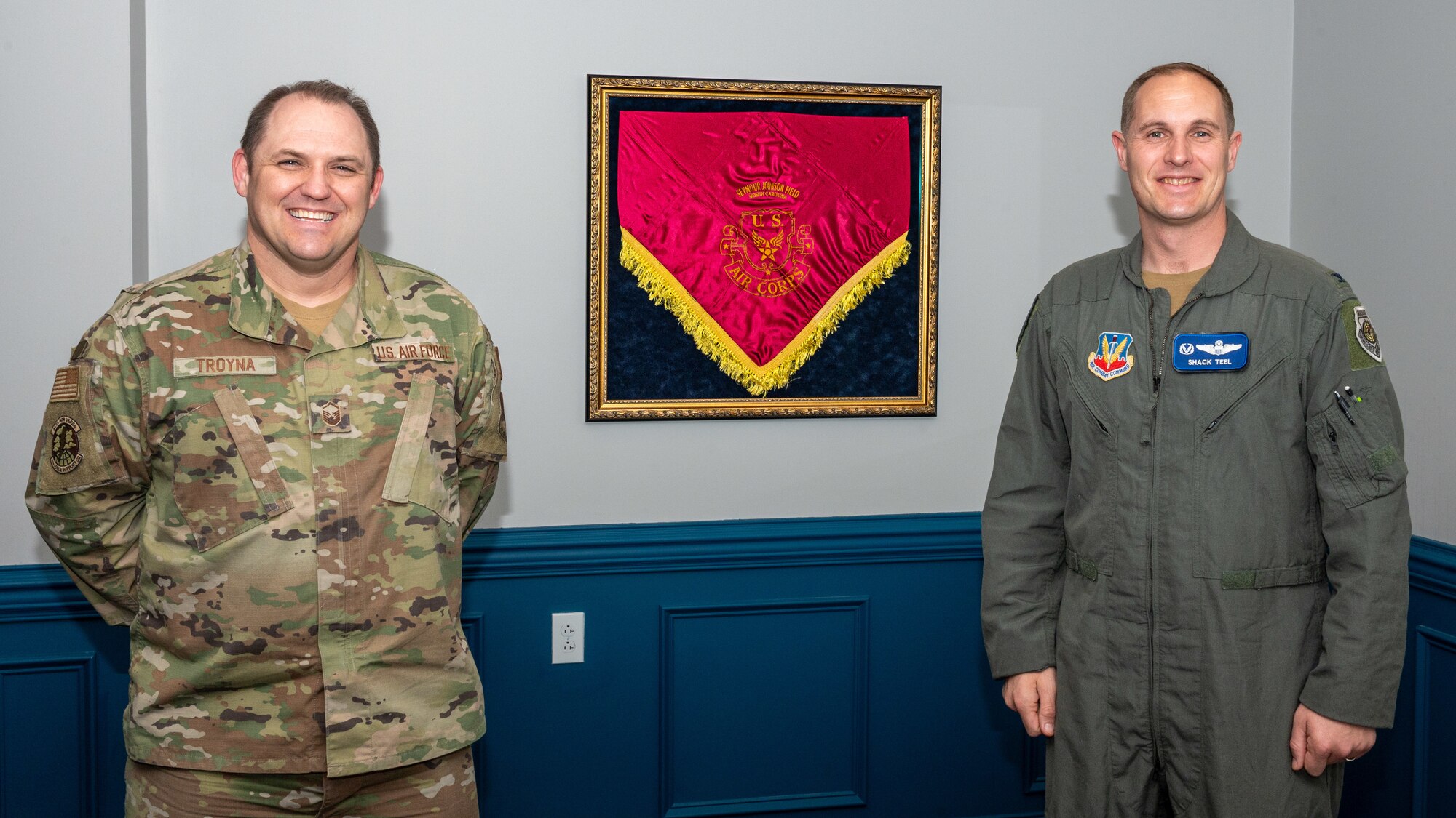 U.S. Air Force Col. Lucas Teel, right, 4th Fighter Wing Commander and Master Sgt. Jason Troyna, left, 4th Civil Engineer Squadron development advisor, pose in front of an antique ceremonial tablecloth at Seymour Johnson Air Force Base, North Carolina, March 14, 2024. Between 1941 and 1946 when SJAFB was called Seymour Johnson Field, which was under Army Air Forces command, the tablecloth was used for ceremonial purposes. (U.S. Air Force photo by Airman 1st Class Leighton Lucero)