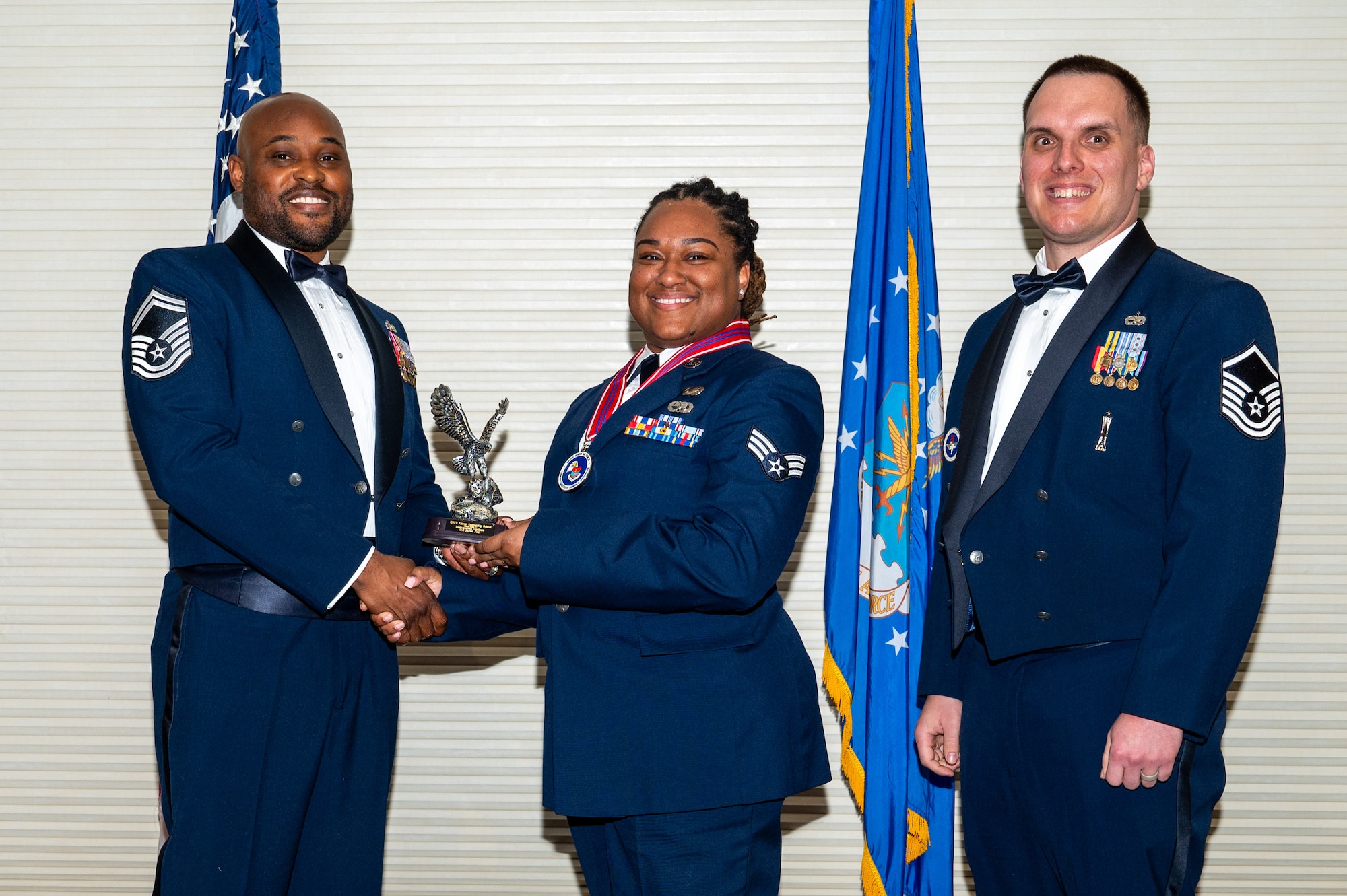 Senior Airman Janee Fair, center, assigned to the 4th Maintenance Group, receives the Distinguished Graduate Award from Senior Master Sgt. Oliver Missick, 4th Fighter Wing Safety Office superintendent, left, and Master Sgt. Dylan Lightfoot, 4th Munitions Squadron alternate mission equipment section chief, right, during the Airman Leadership School class 24-C graduation ceremony at Seymour Johnson Air Force Base, North Carolina, Mar. 20, 2024. Students who received the Distinguished Graduate Award displayed effective teamwork, academic excellence and leadership skills. (U.S. Air Force photo by Airman Rebecca Tierney)