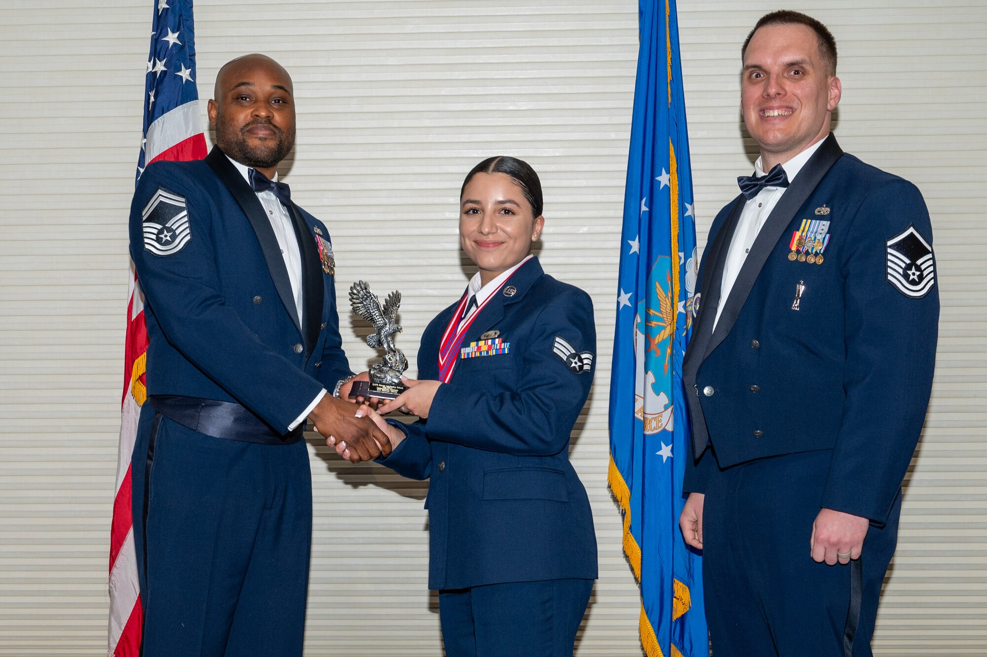 Senior Airman Hannah Garcia, center, assigned to the 335th Fighter Squadron, receives the Distinguished Graduate Award from Senior Master Sgt. Oliver Missick, 4th Fighter Wing Safety Office superintendent, left, and Master Sgt. Dylan Lightfoot, 4th Munitions Squadron alternate mission equipment section chief, right, during the Airman Leadership School class 24-C graduation ceremony at Seymour Johnson Air Force Base, North Carolina, Mar. 20, 2024. Students who received the Distinguished Graduate Award displayed effective teamwork, academic excellence and leadership skills. (U.S. Air Force photo by Airman Rebecca Tierney)