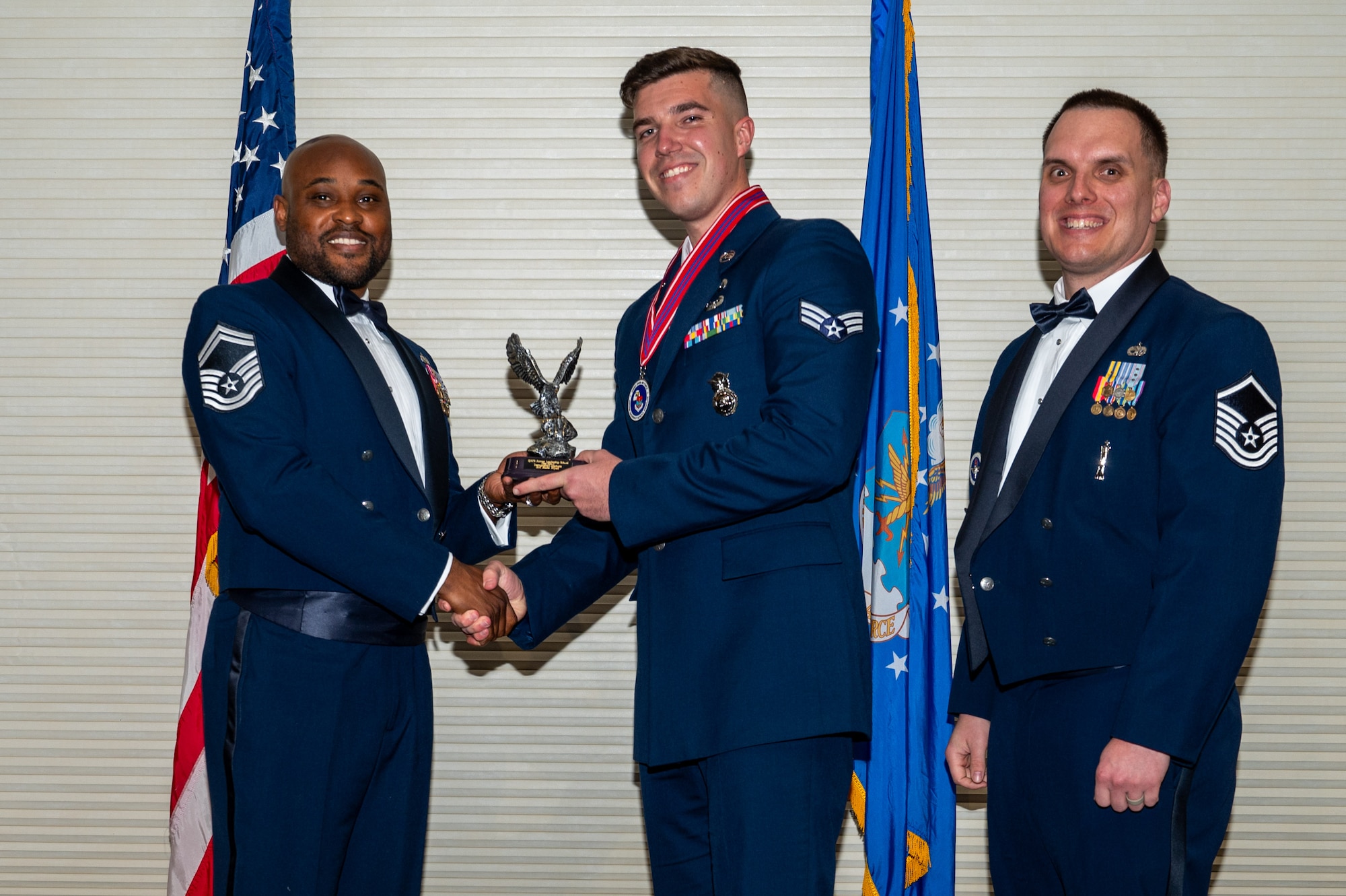 Senior Airman Blake Wyatt, center, assigned to the 4th Security Forces Squadron, receives the Distinguished Graduate Award from Senior Master Sgt. Oliver Missick, 4th Fighter Wing Safety Office superintendent, left, and Master Sgt. Dylan Lightfoot, 4th Munitions Squadron alternate mission equipment section chief, right, during the Airman Leadership School class 24-C graduation ceremony at Seymour Johnson Air Force Base, North Carolina, Mar. 20, 2024. Students who received the Distinguished Graduate Award displayed effective teamwork, academic excellence and leadership skills. (U.S. Air Force photo by Airman Rebecca Tierney)