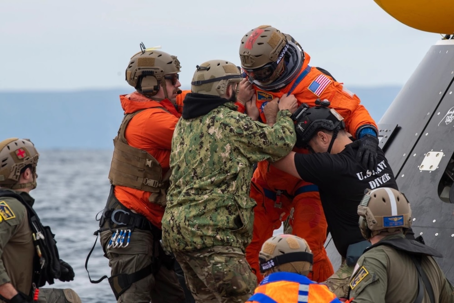 Navy Divers assist astronaut out of crew module test article during Underway Recovery Test 11