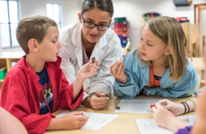 Instructor works with two kids in a classroom environment.