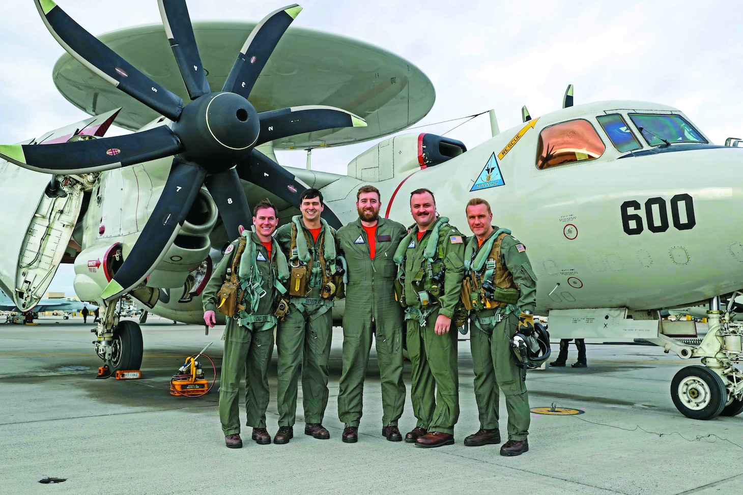 From left to right, assigned to Naval Aviation Warfare Development Command (NAWDC), Carrier Airborne Electronic Warfare Weapons School (CAEWWS), U.S. Navy Lt. Nicholas Tucker, U.S. Navy Lt. Zachary Verissimo, British Royal Navy Lt. Cmdr. Tom Rixon, U.S. Navy Cmdr. Joshua Goodin, and Naval Air Station (NAS) Fallon Commanding Officer Capt. Shane Tanner pose for a photo on the flightline at NAS Fallon, Jan. 26, 2024. Home to the Fighting Saints of Fighter Squadron Composite 13 (VFC-13) and the Naval Aviation Warfare Development Command (NAWDC), NAS Fallon serves as the Navy’s premier tactical air warfare training center.