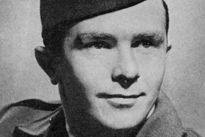 A man in a military cap poses for a photo.