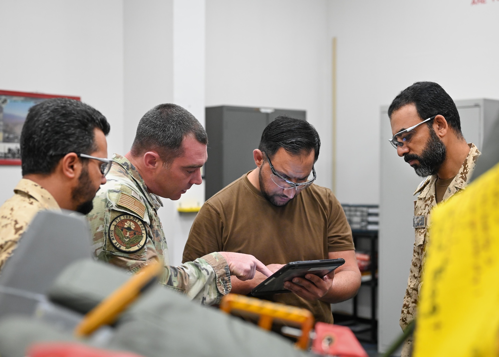 A group of men observe a laptop screen.