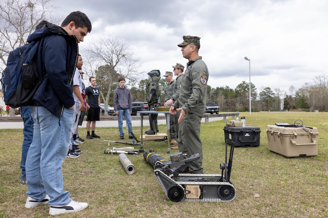 U.S. Marine Corps Master Sgt. Carlos Villareal, Sgt. Kevin Kazimer, and Sgt. Connor Paul, explosive ordnance disposal technicians assigned to Headquarters and Headquarters Squadron, Marine Corps Air Station Cherry Point, explain various pieces of inert ordnance and the equipment used to safely handle ordnance during a military career day at West Craven High School, Vanceboro, North Carolina, March 22, 2024. During the event, the Marines with EOD interacted with students, fielding questions about military occupational specialties and general Marine Corps information. (U.S. Marine Corps photo by Lance Cpl. Lauralle Gavilanes)