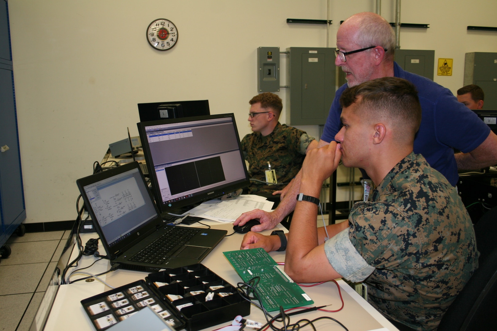 Miniature/Micro-Miniature Module Test and Repair Training Lead Brian Fowler (center) trains U.S. Marine Lance Cpl. Zachary Bentz (left) and Lance Cpl. Joshua Bucher (right) from the 2nd Electronics Maintenance Company. The 2M/MTR program plays a crucial role in ensuring Navy fleet readiness through its innovative solutions for electronic component repair and maintenance (Courtesy Photo).