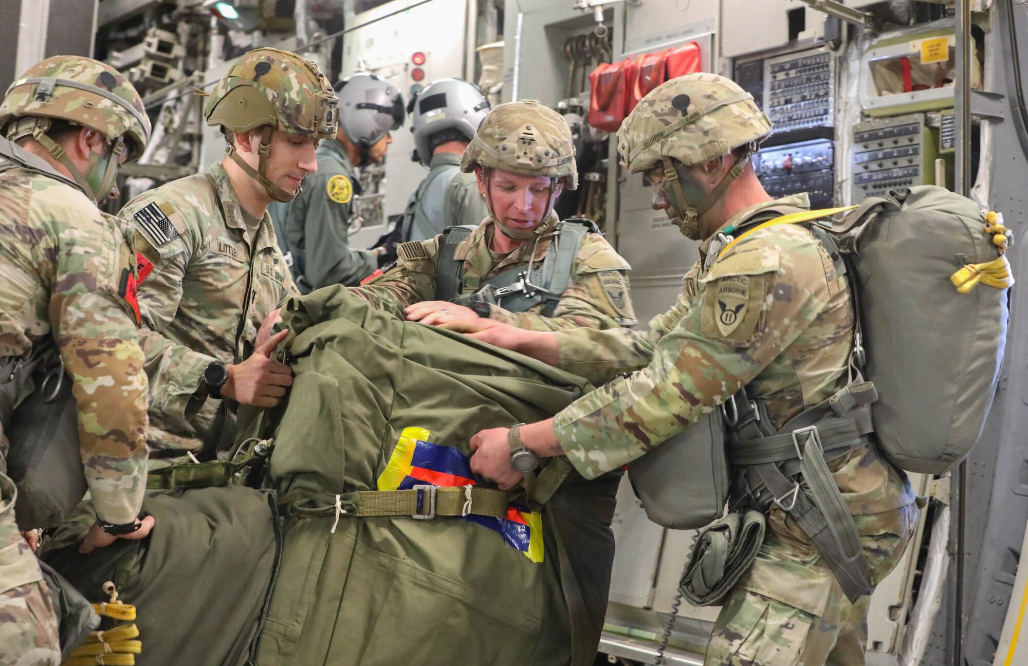 Soldiers pack supplies into a bag on an aircraft.