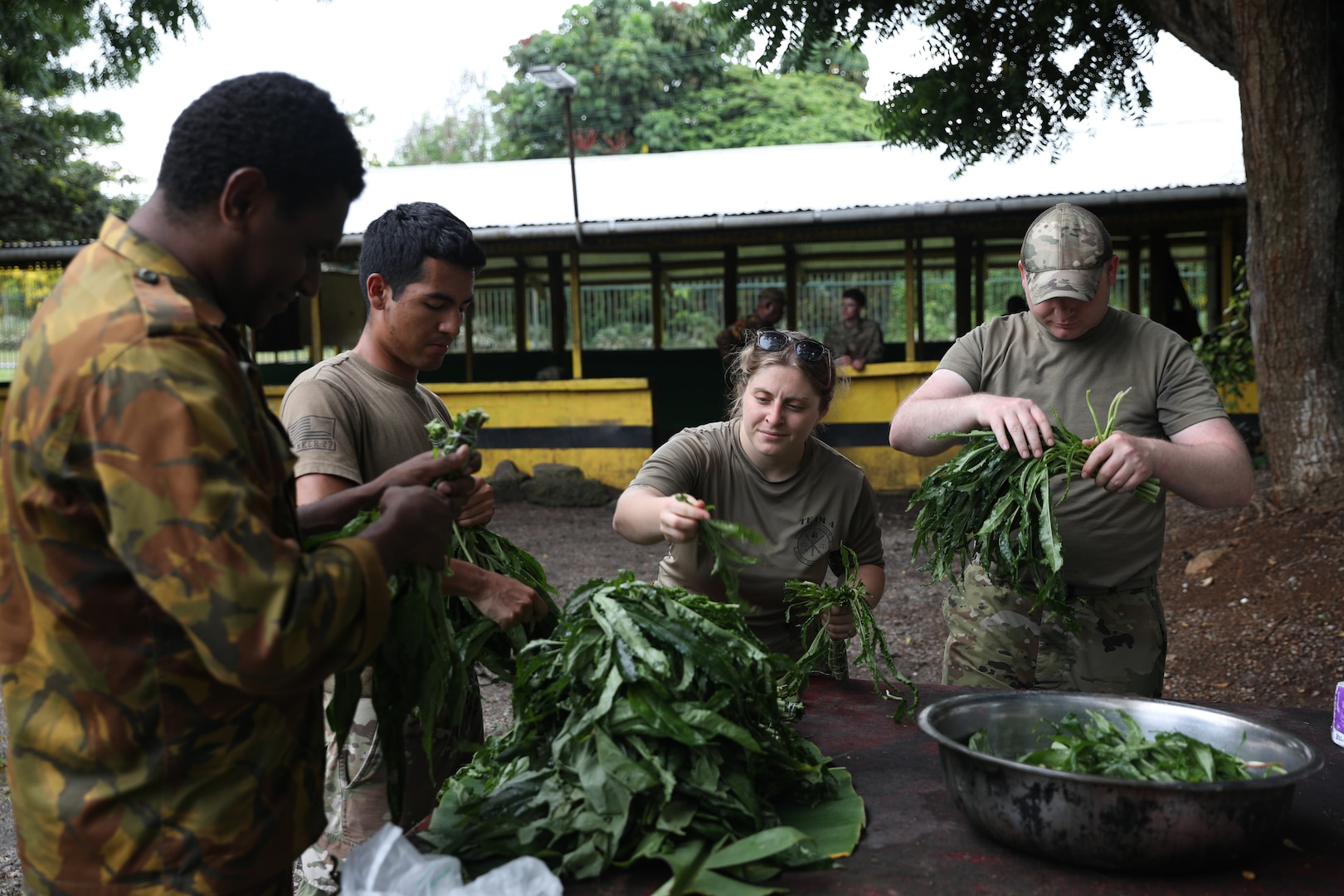 Senior Airman Julia Childers, Staff Sgt. Xavier Medonza and Master Sgt. Cody Beran, Wisconsin Air National Guard security forces members, help prepare food for a meal prepared alongside members of the Papua New Guinea Defence Force military police March 21 during a recent visit by 40 Wisconsin National Guard members to Papua New Guinea in support of the State Partnership Program. This current exchange includes meetings between leadership along with training in instruction, medical, security forces, and collaboration with senior non-commissioned officers. The Wisconsin National Guard and Papua New Guinea began their partnership in 2020 and have since had several key leader engagements and site visits to strengthen that relationship. Wisconsin National Guard photo by Staff Sgt. Kati Volkman