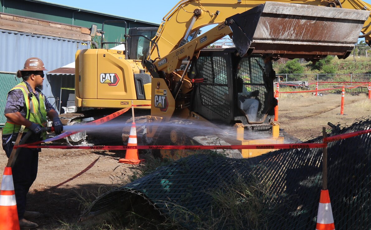 A U.S. Army Corps of Engineers contractor applies water to the ground of a commercial property from outside the exclusion zone during Phase 2 debris removal operations March 22, 2024, in Lahaina, Hawaii. This was the first commercial property debris removal operation for commercial property impacted by the Aug. 8, 2023, wildfires. (USACE photo by Edward Rivera)