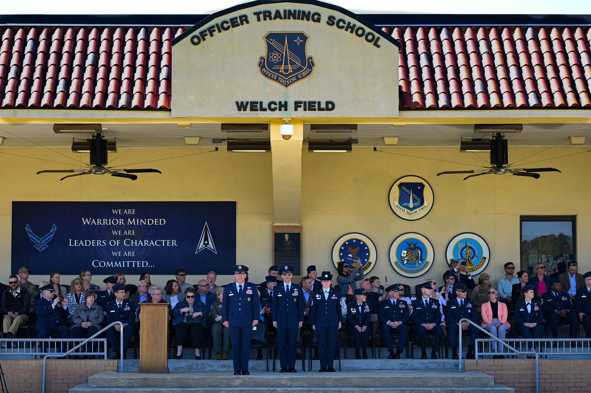 U.S. Air Force Col. Josh Koslov, 350th Spectrum Warfare Wing commander, left, U.S. Air Force Col. Derrick Iwaneko, U.S. Air Force Officer Training School commandant, center, and U.S. Air Force Master Sgt. Candice Davis, OTS training instructor, stand at attention during the OTS graduation parade at Maxwell Air Force Base, AL, March 28, 2024. The program consists of 30 hours of pre-requisite distance learning and eight weeks of military training and leadership development for college graduates. (U.S. Air Force photo by Capt. Benjamin Aronson)