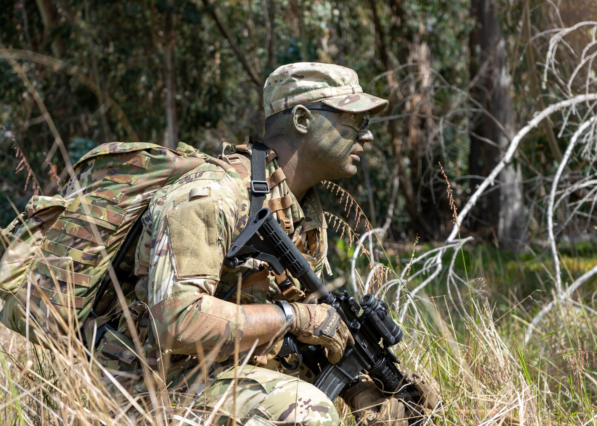 A man in uniform sits in the woods.