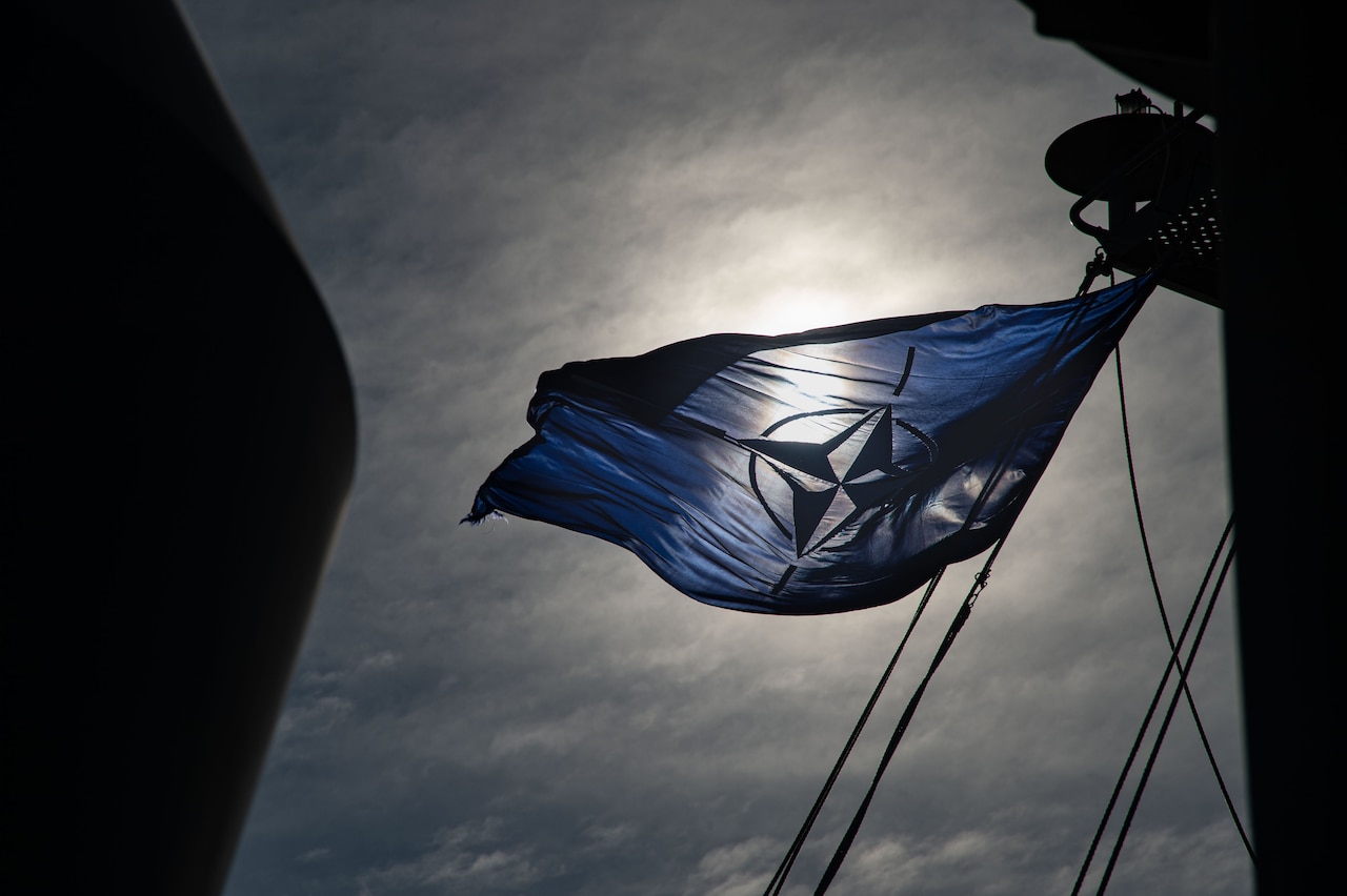 A NATO flag is displayed aboard a ship.