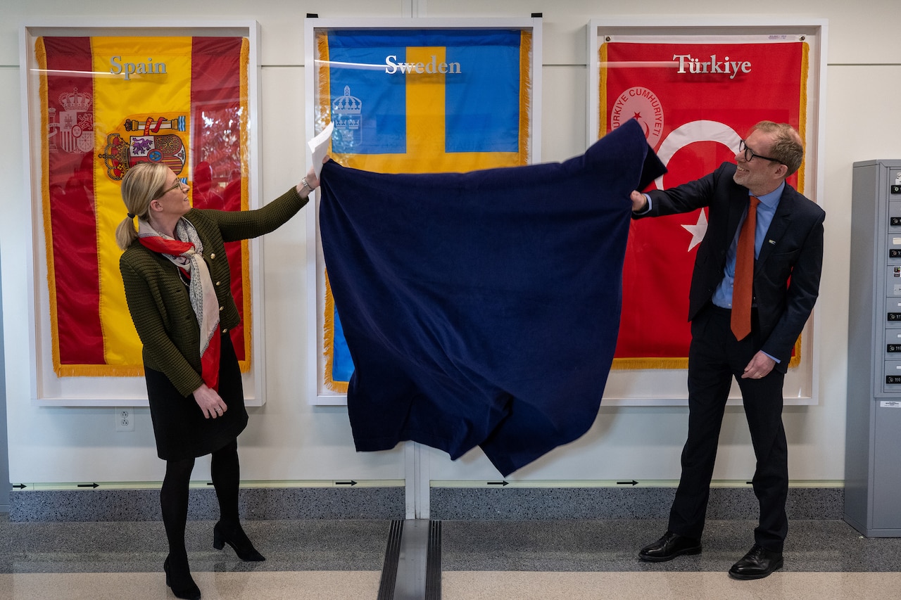 Two civilians uncover a foreign flag hanging on a wall.