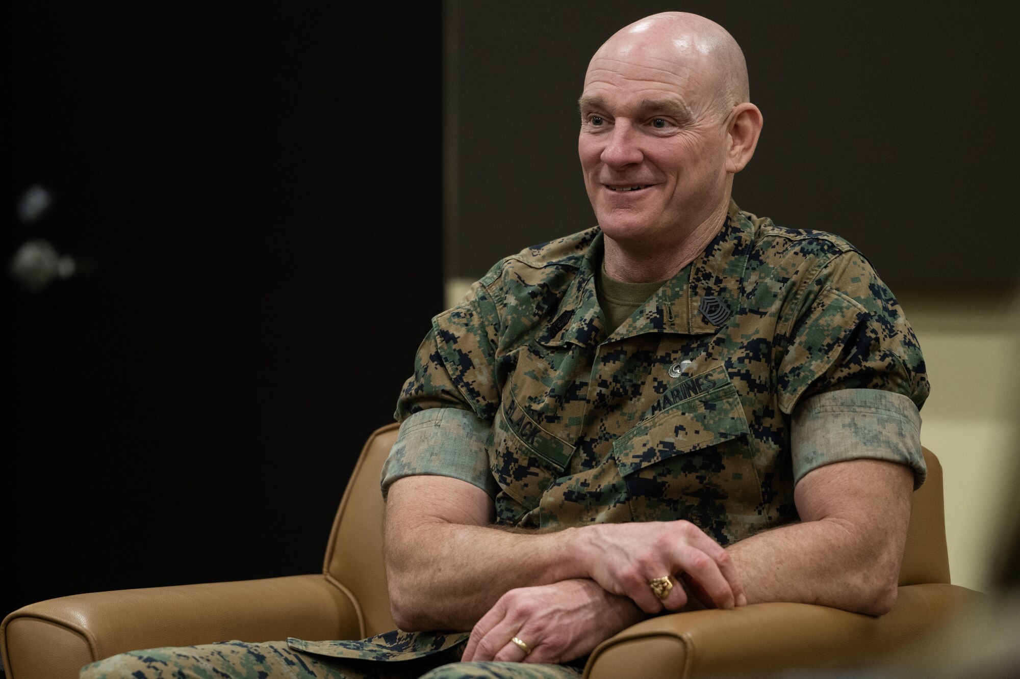 Military member sitting and smiling.