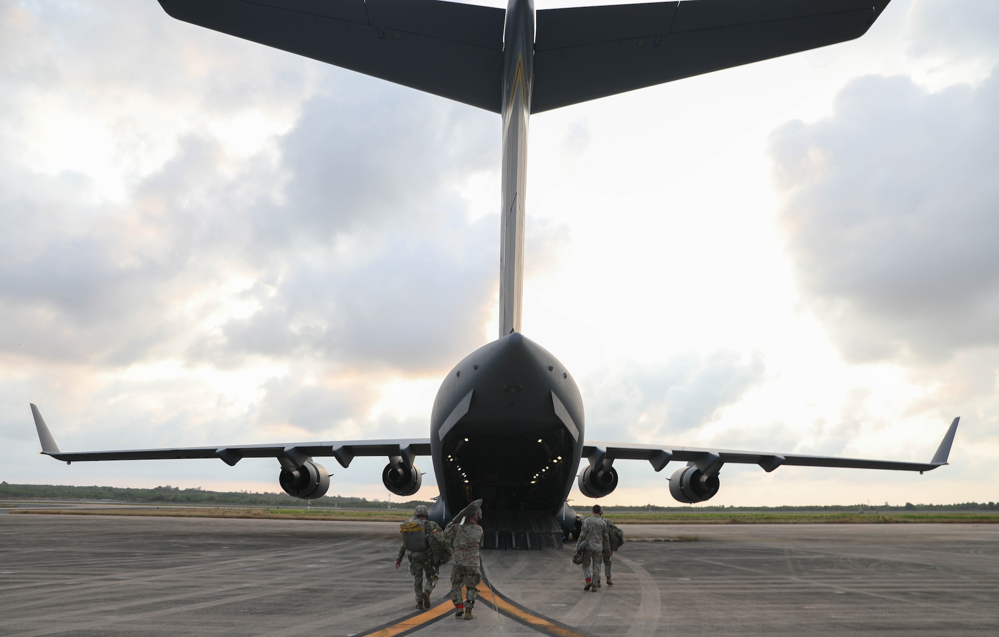 Soldiers enter the back of a large aircraft.