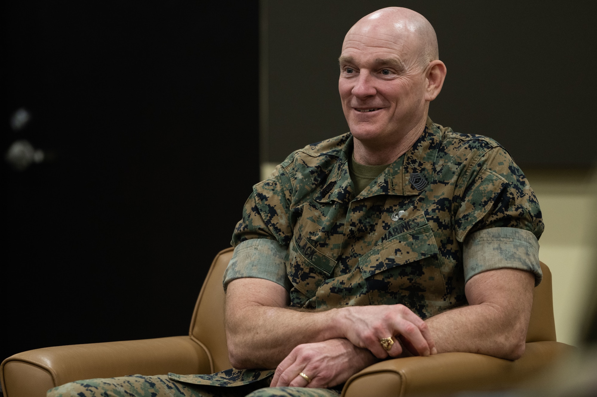 Military member sitting and smiling.