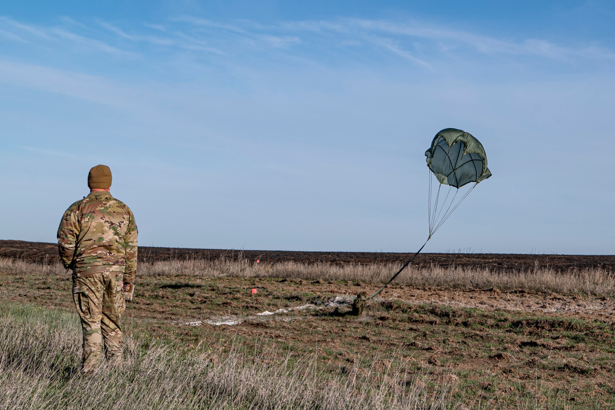 A U.S. Air Force rescue Airman assigned provides ground support for an aerial cargo drop at Smoky Hill Air National Guard Range, Kansas, March 26, 2024. The cargo drop was part of the Rescue Rodeo, a rescue training event and competition. Each team earned points in the competition based on how close the cargo landed to the ground target. (U.S. Air Force photo by Airman 1st Class Leonid Soubbotine)