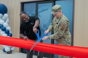 two people cut a ribbon with giant scissors