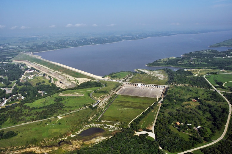 Aerial view of a lake with a dam in the middle and grass in the foreground.