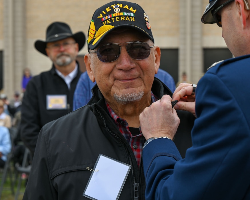 U.S. Air Force Col. Christopher Corbett, 17th Training Wing deputy commander, pins Bobby Cortez, Vietnam War veteran, during the 2024 National Vietnam War Veteran Memorial and Pinning Ceremony at the Weyandt-Eddy Memorial Plaza, Norma Brown Headquarters building, Goodfellow Air Force Base, Texas, March 29, 2024. The Vietnam War Veteran commemorative lapel pin includes an eagle’s head representing courage, stripes representing the nation's flag and six stars representing the allies during the war.