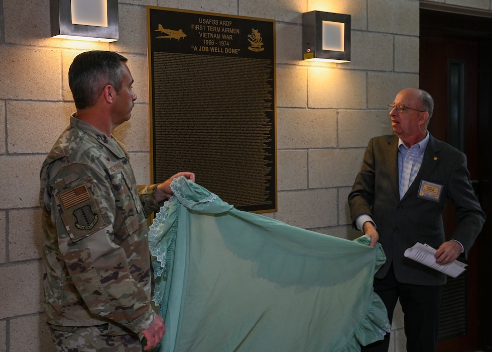 U.S. Air Force Col. Ian Rybczynski, 17th Medical Group commander, and Ronald “JJ” Graham, Freedom Through Vigilance Association Heritage Chapter President, unveil the United States Air Force Security Service Airborne Radio Direction Finding mission First Term Airmen Vietnam War Plaque at the Norma Brown Headquarters building, Goodfellow Air Force Base, Texas, March 29, 2024. The plaque was dedicated to the First Term Airmen who served on the EC-47 during the Vietnam War for one contract.