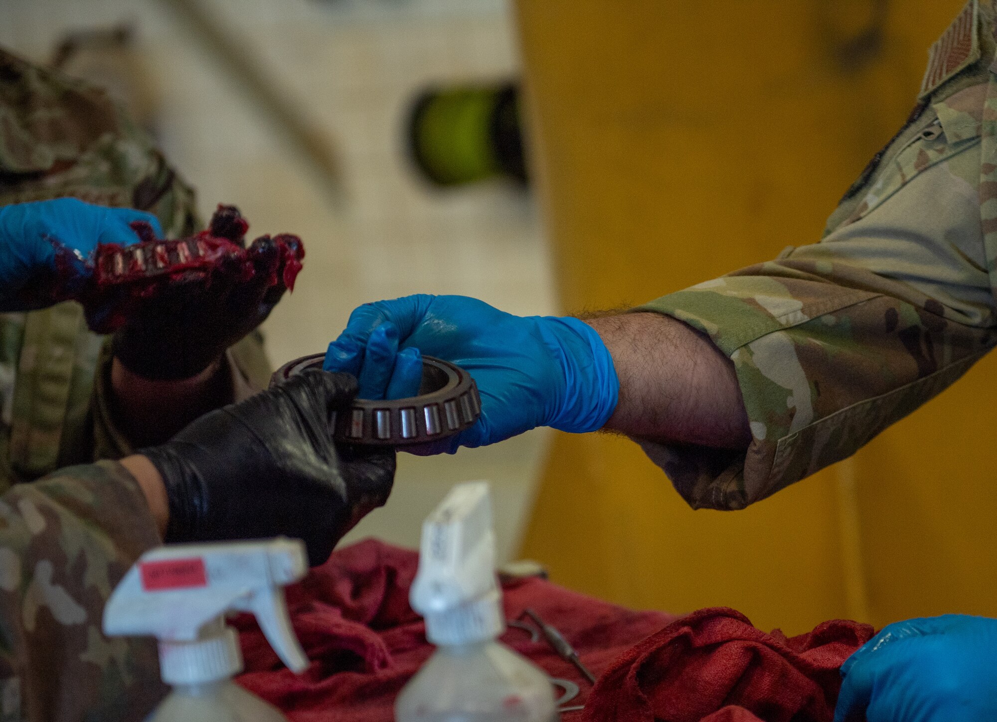 U.S. Air Force Col. Paul Sheets, 23rd Wing commander, hands a landing-gear bearing to an Airman assigned to the 71st Rescue Generation Squadron at Moody Air Force Base, Georgia, March 25, 2024. Sheets learned how Airmen clean and inspect bearings prior to replacing a tire on an HC-130J Combat King II. (U.S. Air Force photo by Airman Cade Ellis)