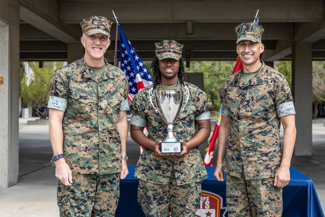 U.S. Marine Corps Cpl. Jefferson, center, a new join program advisor with Headquarters and Service Company, 1st Supply Battalion, 1st Marine Logistics Group poses for a photo with Brig. Gen. Woodworth, left, the commanding general of Marine Corps Installations West, Marine Corps Base Camp Pendleton, and Sgt. Maj. Cabrera, the sergeant major of MCI-West, MCB Camp Pendleton during the 2024 Camp Pendleton Male and Female Marine Athlete of the Year ceremony at MCB Camp Pendleton, California, April 4, 2024. Jefferson was recognized for her efforts playing as a point-guard for the All-Marine Women’s Basketball team for two years.(U.S. Marine Corps photo by Lance Cpl. Watts)