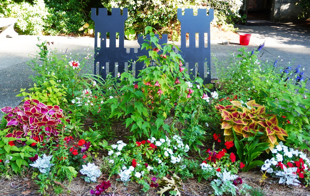 A bed of flowers around a metal fabricated castle frame.